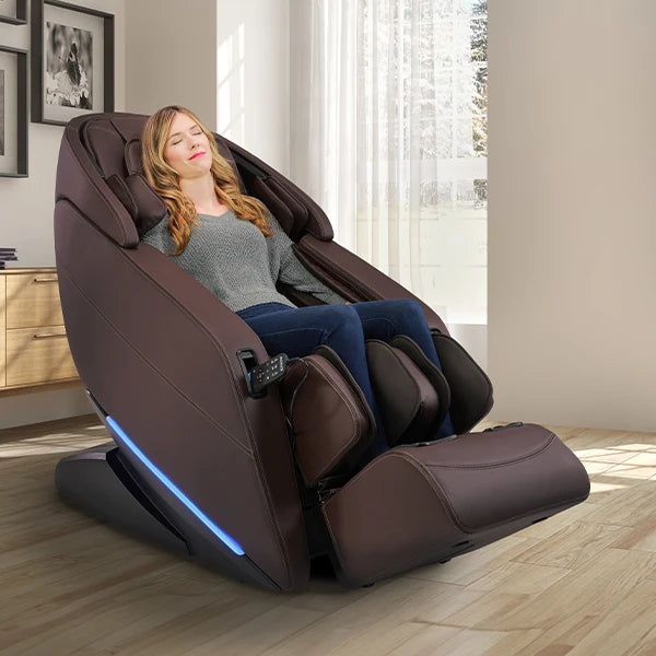 Kyota Yugana M780 brown massage chair in zero gravity position featuring 4D massage rollers, SL-track technology, full body air compression, deep calf and foot massage, and ambient LED lighting in a modern living room