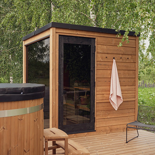 ThermaSol Nordic Dawn outdoor sauna cabin made of thermo-pine wood with glass door and WiFi heater installed in backyard wellness setup