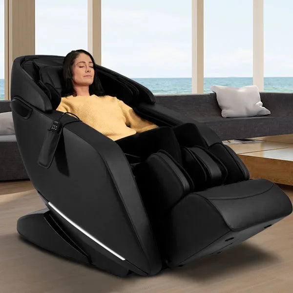 Kyota Genki M380 black zero gravity massage chair with full body air compression and foot rollers, shown in a modern living room with a user relaxing