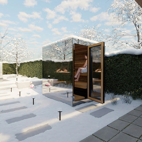 ThermaSol Vue mirrored glass outdoor sauna cabin in snowy backyard with door open showing warm wood interior and person relaxing inside